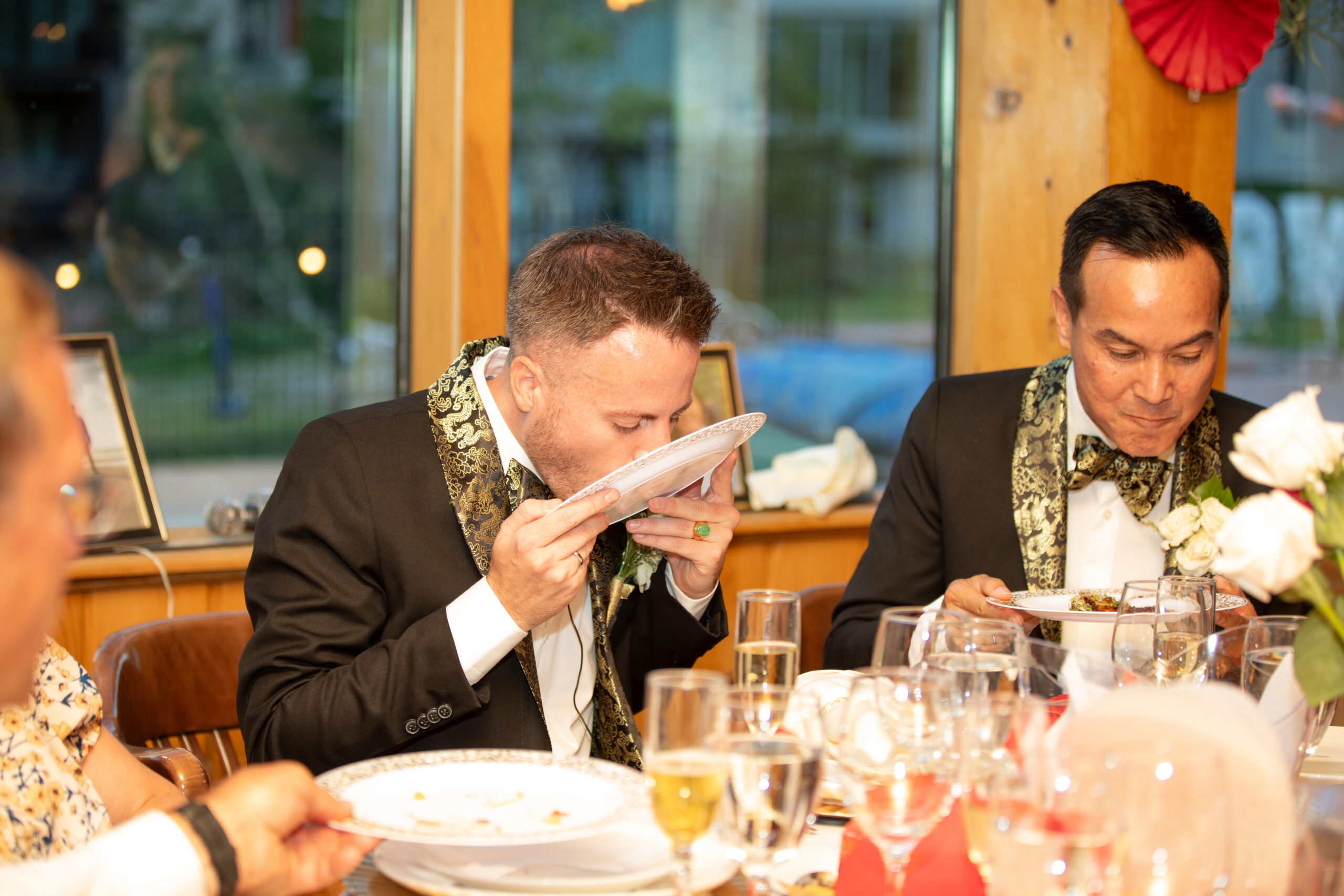 The couple participating in the “Lick a Plate” activity at their wedding dinner.